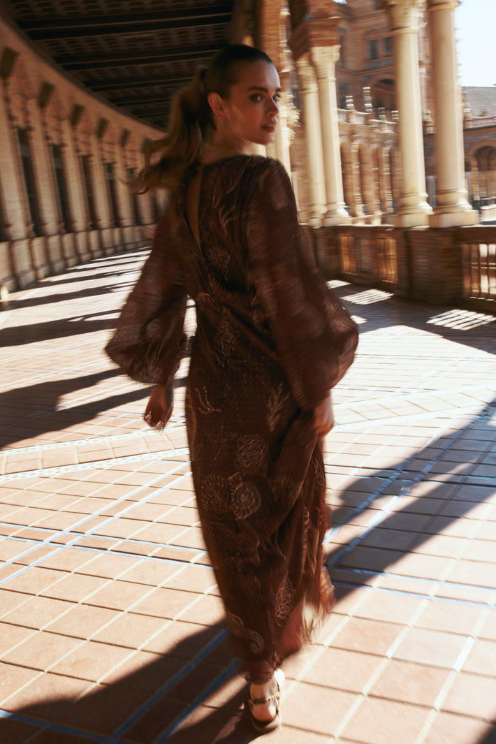 Ibana Jurk Danoli Shell Marron met flowy stof en elegante snit, zichtbaar op de afbeelding.