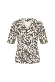 Mi Piace Travel Top met abstracte print en diepe kleuren, getoond op een model. Moderne, stijlvolle reisoutfit.