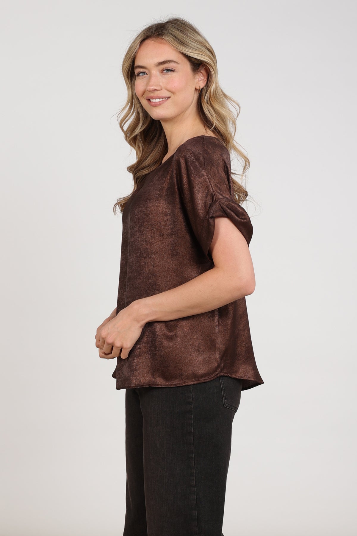 Nukus Irene Shiny Chocolade top, glanzende stof, stijlvolle damesmode, close-up van de bovenkant met strapdetails.