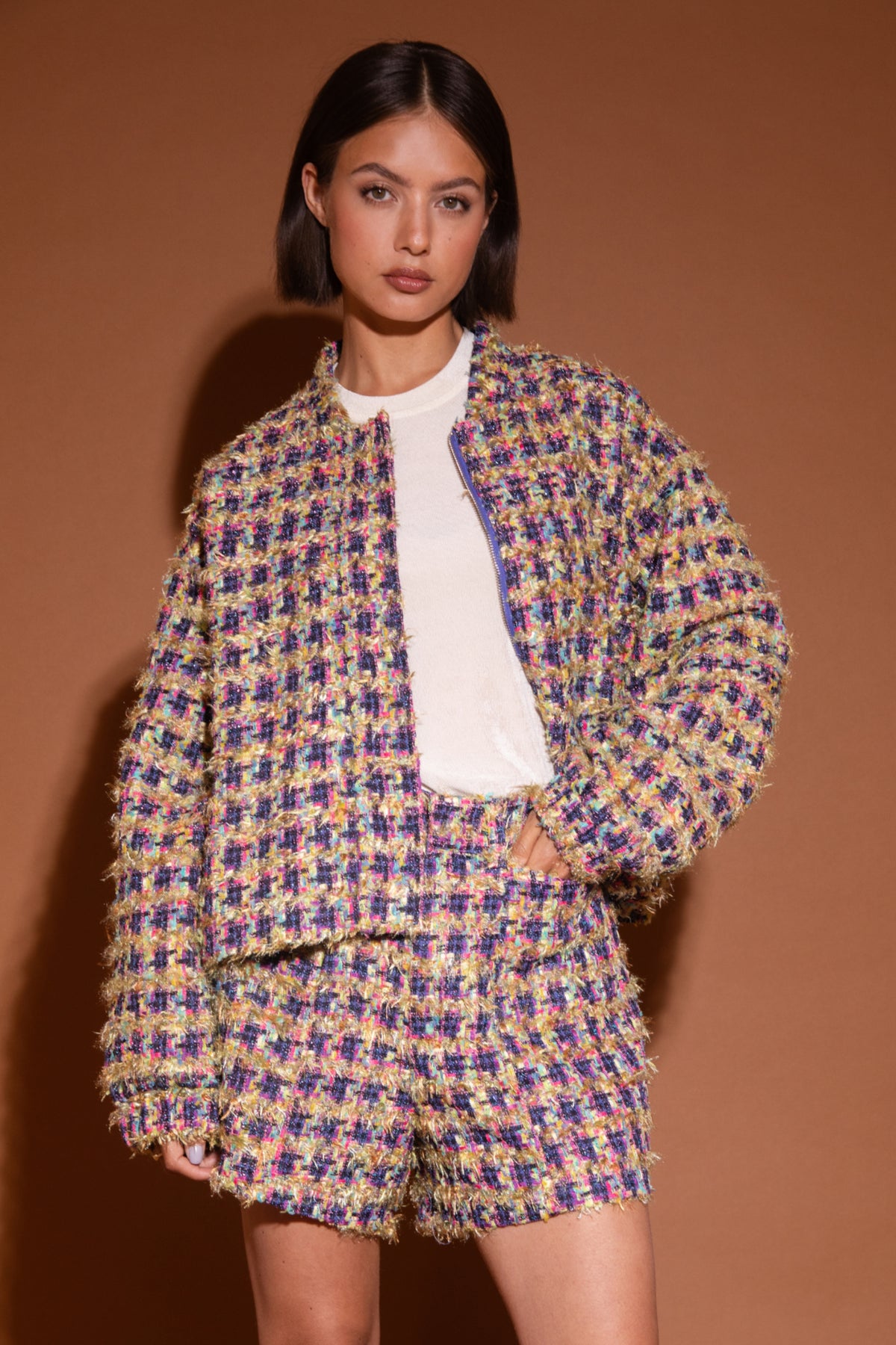 Stijlvolle bomber jas van Studio Amaya met kleurrijke bloemprint en multi-kleurige details, gedragen door een model.