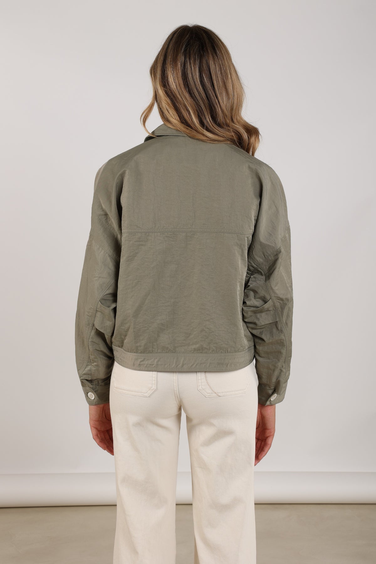 Nukus Lia Army jas in kaki met capuchon, zichtbaar in studiofoto, met stevige stof en modieuze militaire stijl.