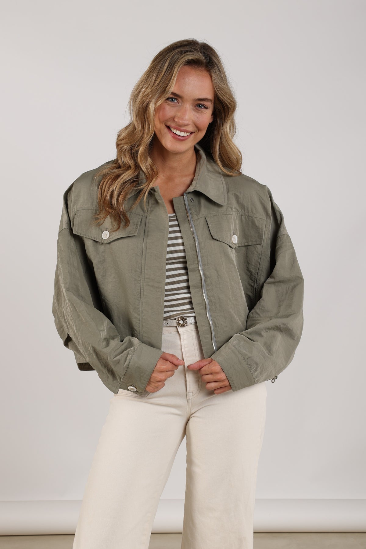 Nukus Lia Army jas in kaki kleur, getoond in studiofoto, met ritssluiting en capuchon, geschikt voor outdoor activiteiten.